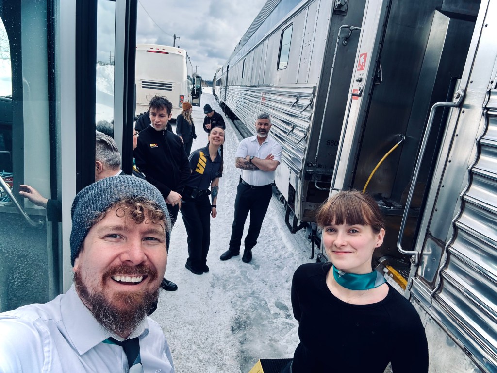 train workers standing outside of a train smiling
