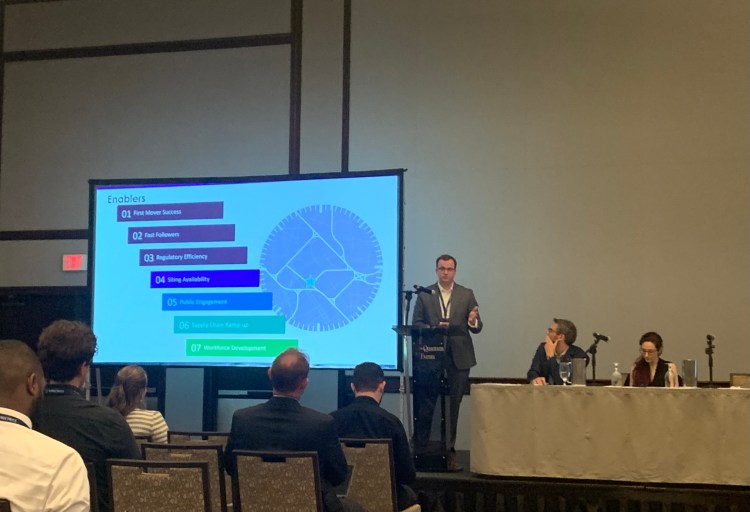 a man giving a powerpoint presentation on nuclear energy at a conference