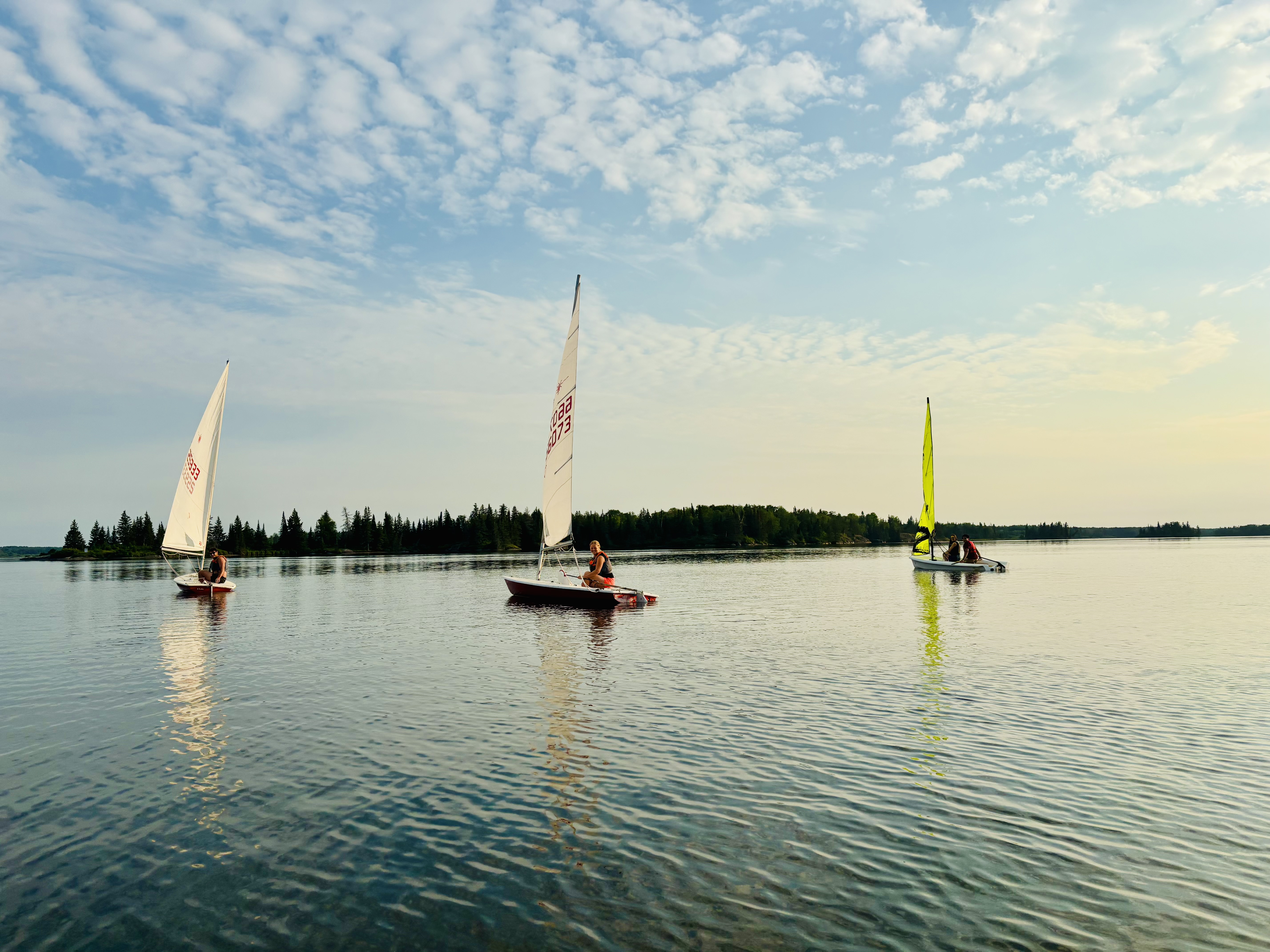 3 sailboats sailing in a sunset