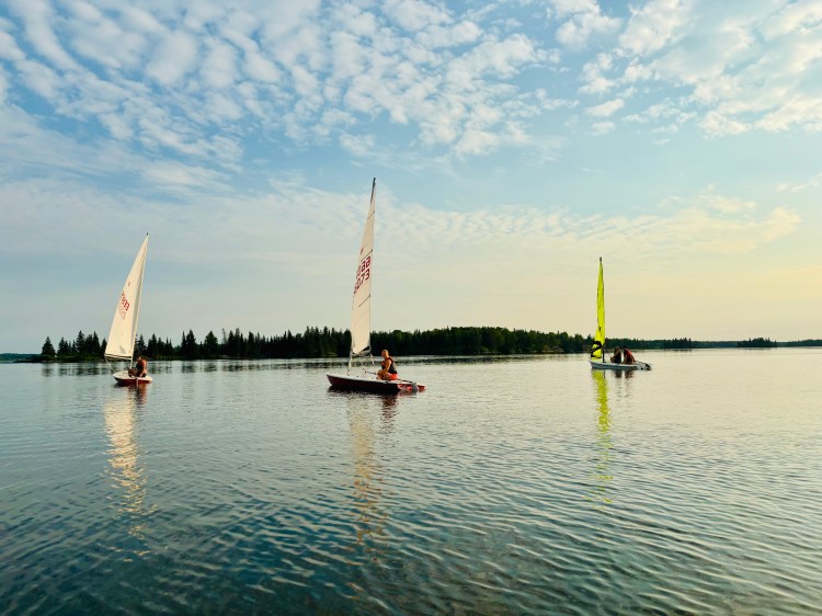 3 sailboats sailing in a sunset